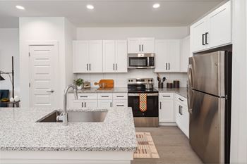 A modern kitchen with white cabinets and stainless steel appliances.